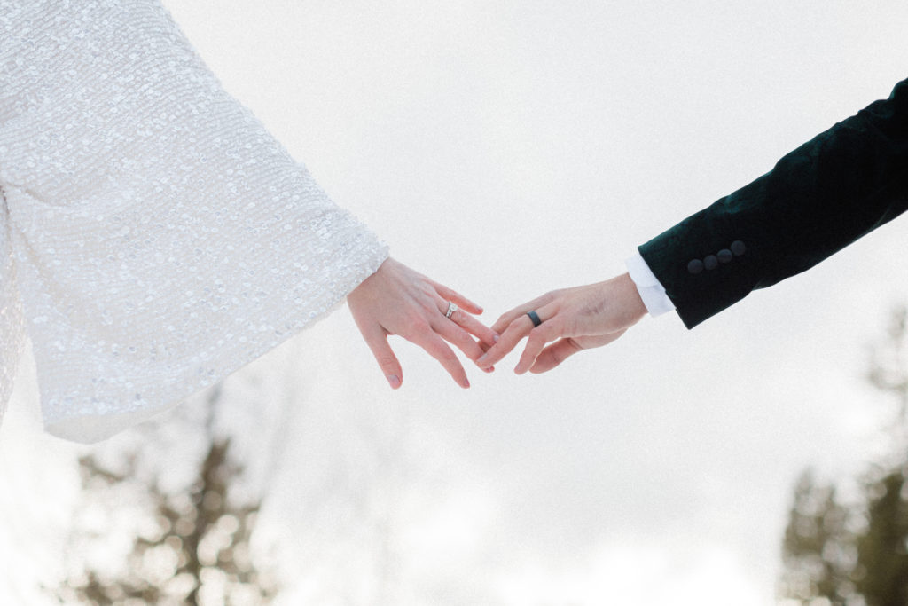 bride and groom eloping in Breckenridge, Colorado during the winter and holding hands showing their rings