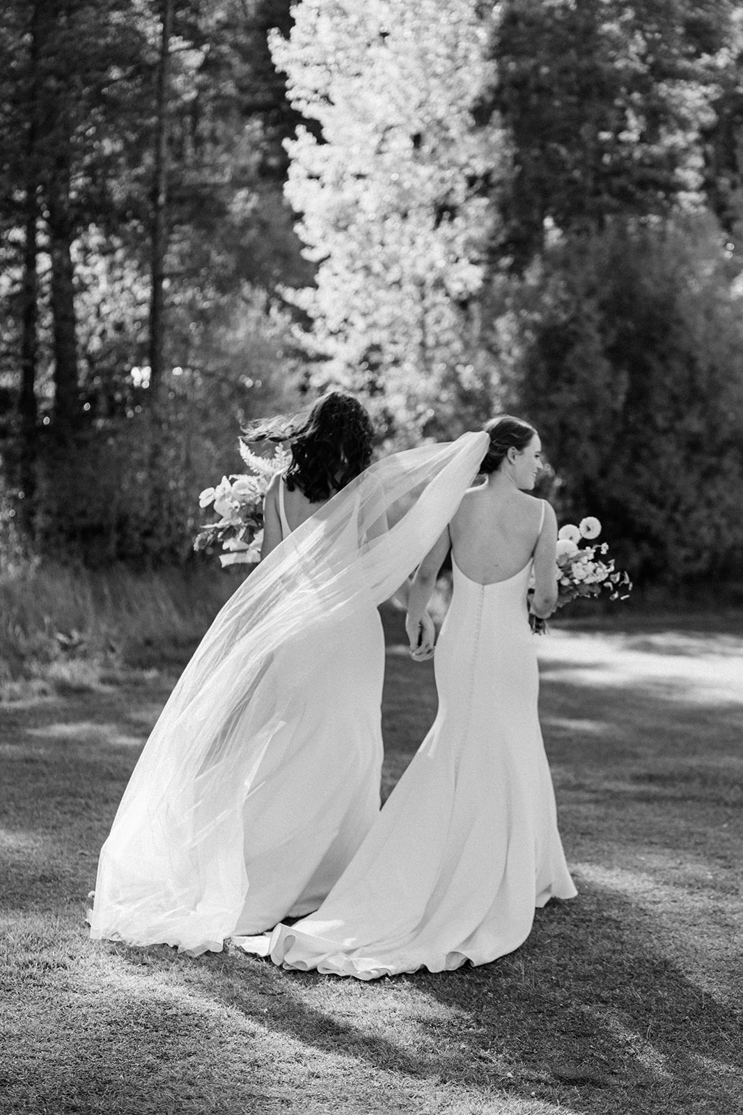 blurry, soft focus, black and white photo of lgbtq lesbian two brides walking away from their ceremony spot at camp hale