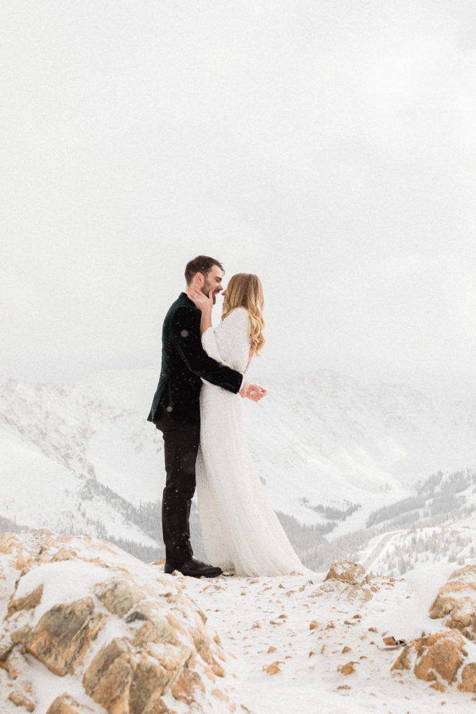 bride and groom kiss during magical snowy mountain white winter elopement at the top of loveland pass colorado 