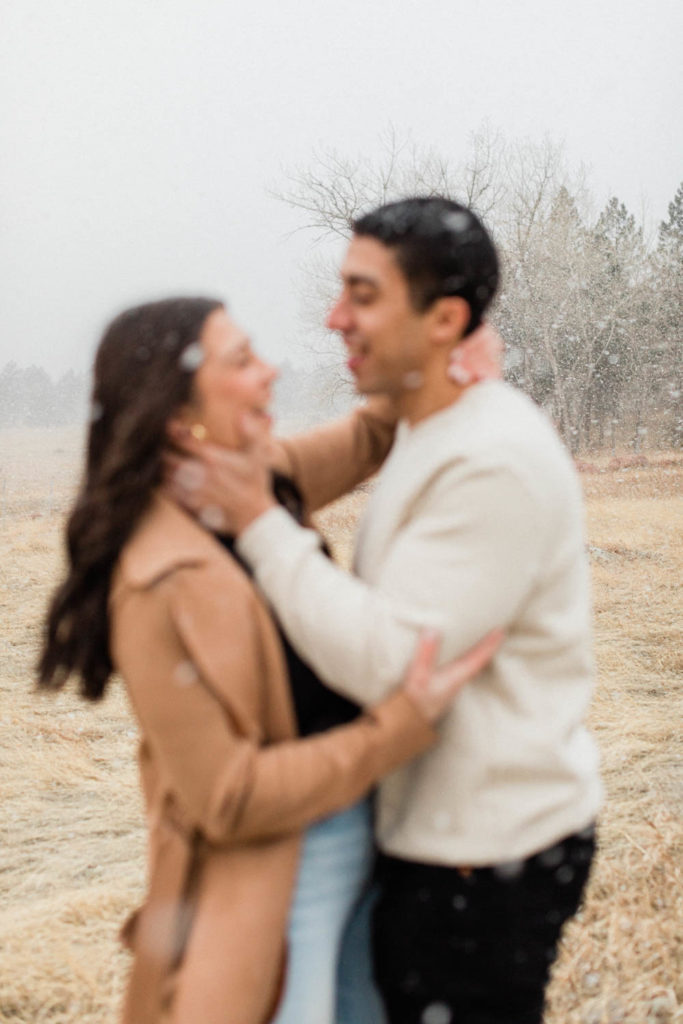  stylish couple kissing during their snowy Boulder engagement session holding hands with the Colorado Rocky Mountains behind them with Colorado elopement photographer Diana Coulter