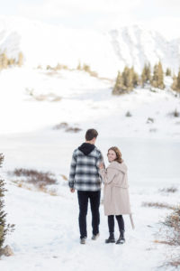 Woman looking back towards the camera while walking through the mountains after surprise mountaintop proposal on Loveland Pass in Breckenridge, Colorado.
