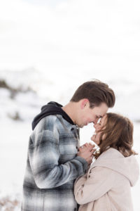 Close up photo of newly engaged couple holding hands with their foreheads together kissing and laughing and enjoying each other on top of a snowy mountain in Breckenridge, Colorado