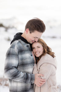 Close up photo of newly engaged couple holding hands with their foreheads together kissing and laughing and enjoying each other on top of a snowy mountain in Breckenridge, Colorado
