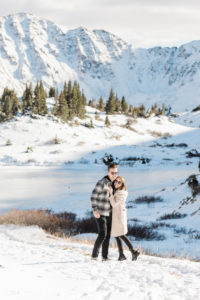 couple smiling together on top of a snowy mountain after surprise proposal