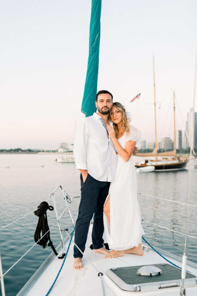 couple standing on a sailboat at sunrise on Lake Michigan in Chicago for the engagement session