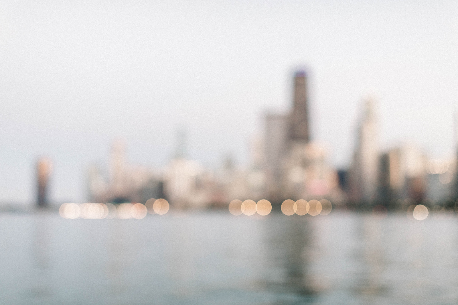 blurry photo of the iconic Chicago Skyline at sunset during blur hour when the lights are bokeh and blurred during a Chicago engagement session
